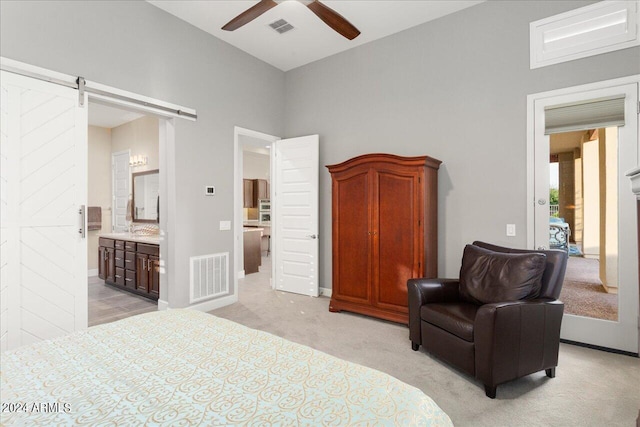 carpeted bedroom with ceiling fan, ensuite bathroom, and a barn door