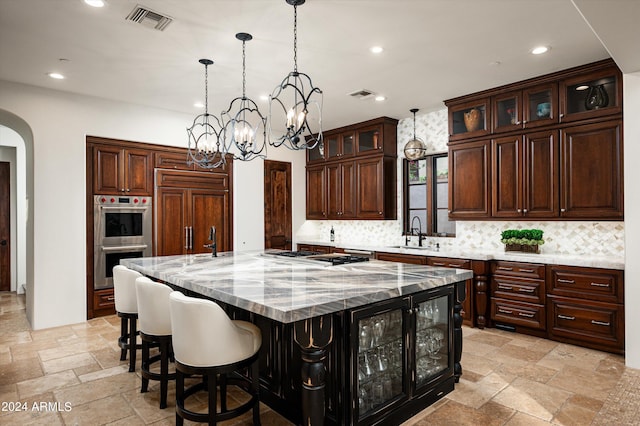 kitchen with hanging light fixtures, stainless steel appliances, an inviting chandelier, and a large island