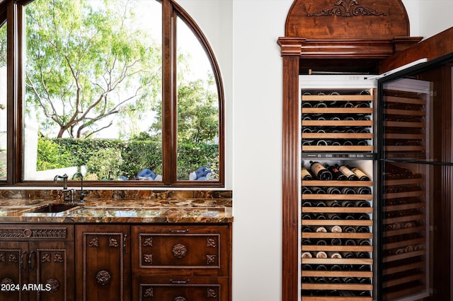 wine cellar featuring beverage cooler, a healthy amount of sunlight, and sink