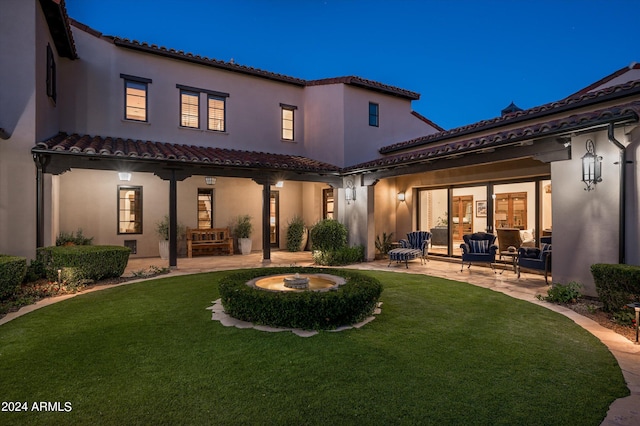 back house at twilight featuring a yard and a patio