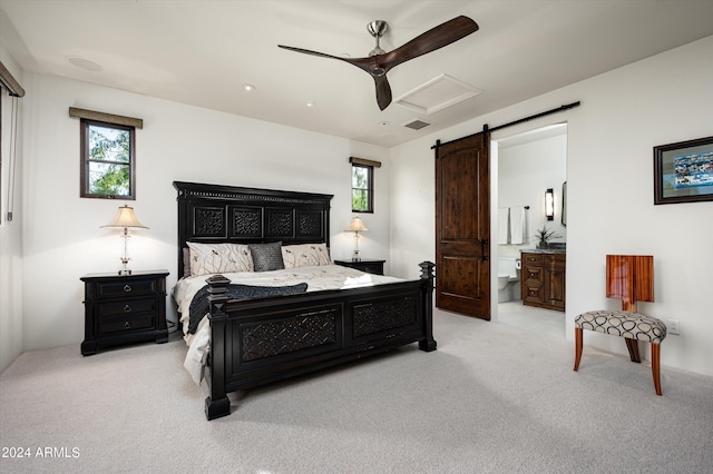 bedroom with a barn door, ceiling fan, light colored carpet, and connected bathroom