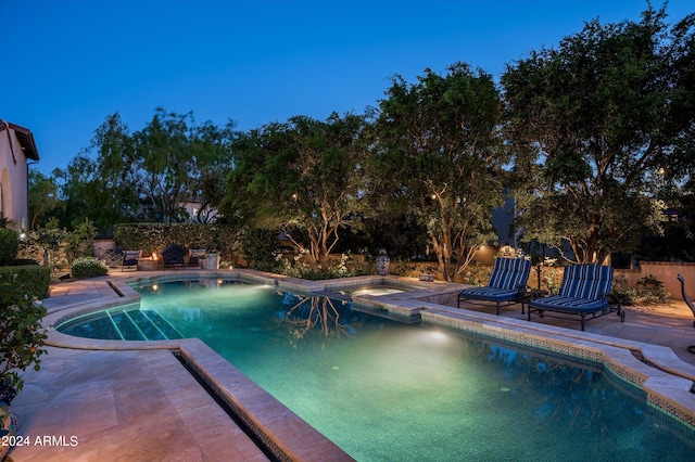 pool at night featuring a patio area