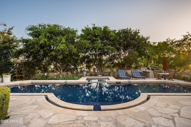 pool at dusk featuring a patio area