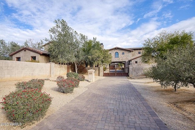 8000 E Mariposa Grande Dr, Scottsdale, AZ 85255 - mediterranean / spanish-style home featuring stucco siding, a gate, fence, and stone siding