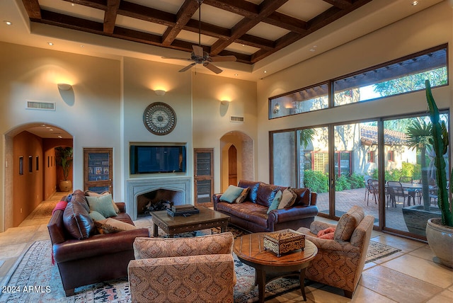 living room with beam ceiling, ceiling fan, a towering ceiling, and coffered ceiling