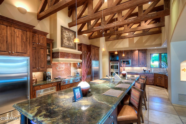 kitchen featuring a large island, high vaulted ceiling, tasteful backsplash, and built in appliances