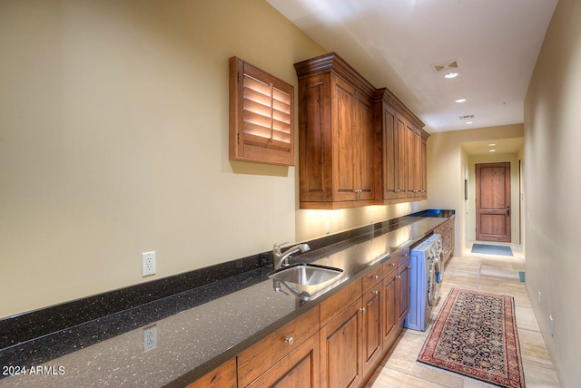 kitchen featuring sink, dark stone countertops, and washer / clothes dryer