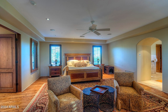 bedroom featuring ceiling fan, light hardwood / wood-style flooring, and multiple windows