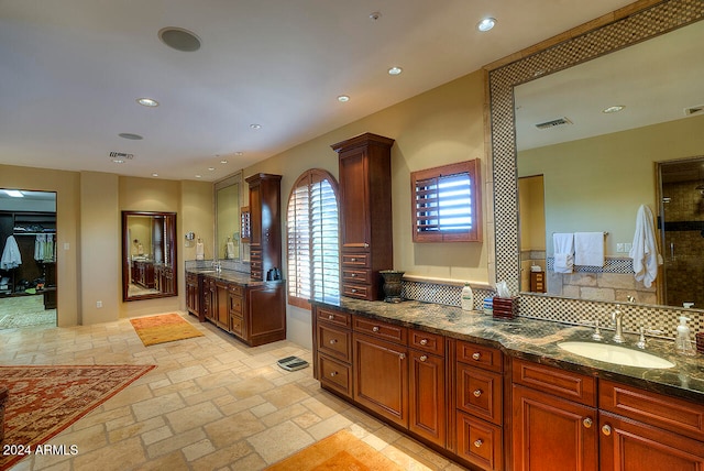 kitchen featuring tasteful backsplash, dark stone counters, and sink