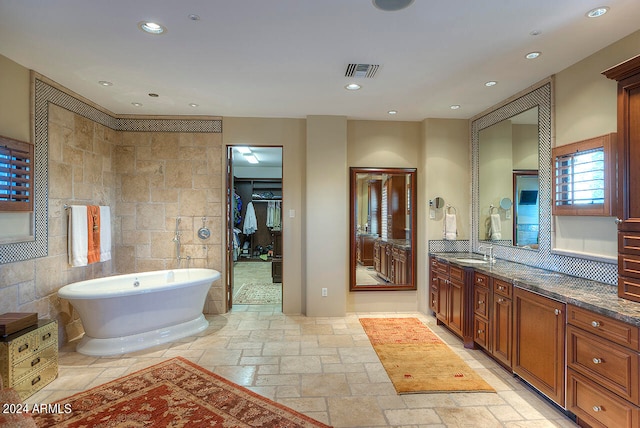 bathroom featuring tile walls, vanity, and a bathing tub