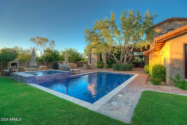 view of pool with an in ground hot tub, exterior fireplace, a yard, and a patio