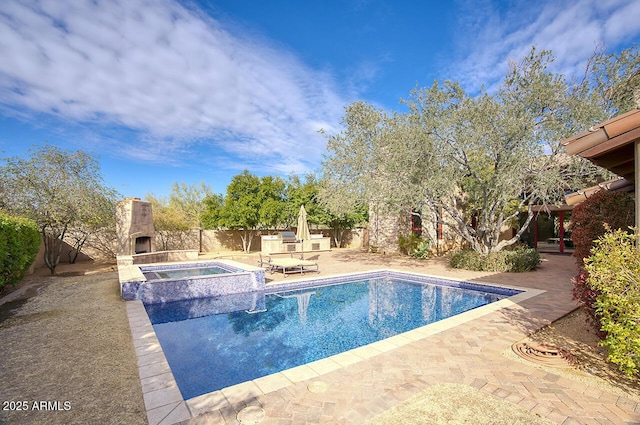 view of pool with an outdoor fireplace, an in ground hot tub, and a patio