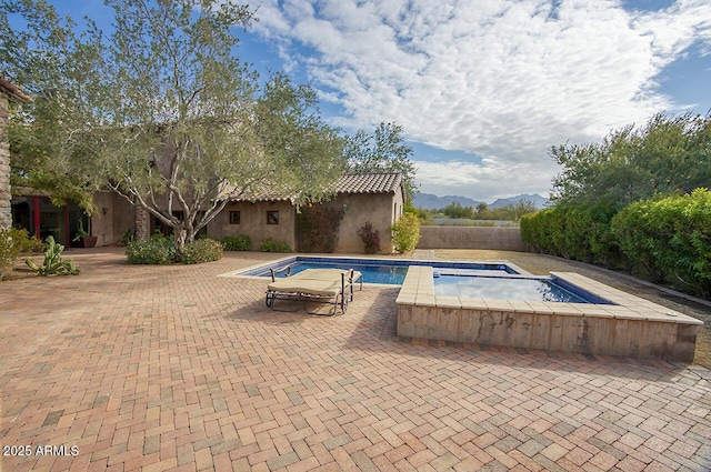 view of pool featuring an in ground hot tub, a patio area, and a mountain view