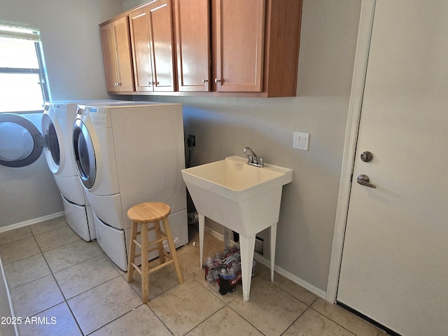 clothes washing area featuring cabinets, light tile patterned flooring, and washer and clothes dryer