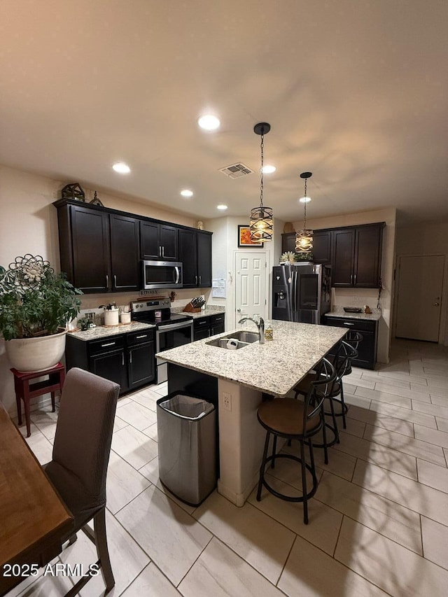 2254 E University Dr Unit 4, Mesa, AZ 85213 - kitchen with appliances with stainless steel finishes, an island with sink, a breakfast bar, light stone counters, and hanging light fixtures