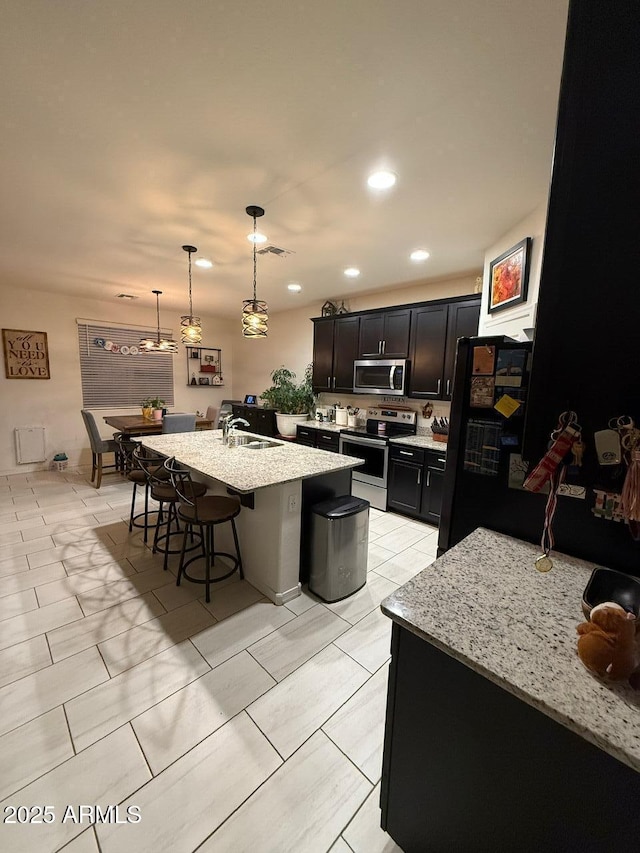 2254 E University Dr Unit 4, Mesa, AZ 85213 - kitchen with stainless steel appliances, a breakfast bar area, an island with sink, light stone countertops, and recessed lighting