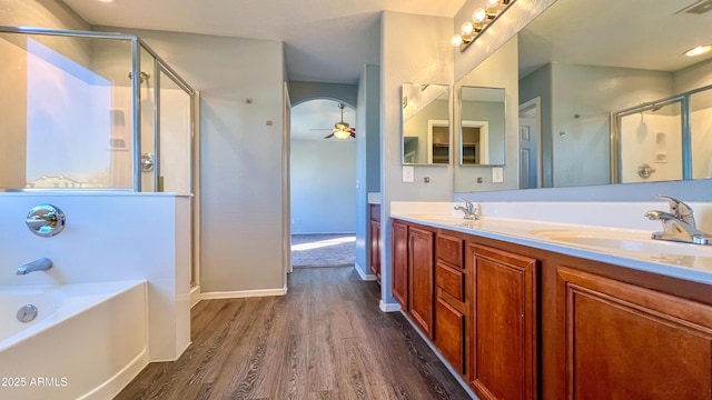 bathroom with vanity, hardwood / wood-style flooring, plus walk in shower, and ceiling fan