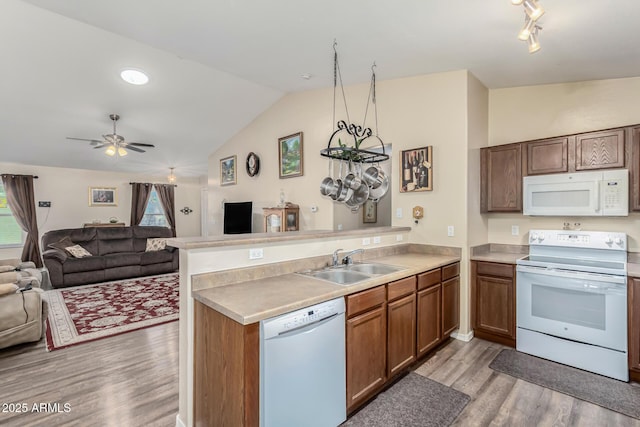 kitchen featuring white appliances, kitchen peninsula, ceiling fan, sink, and lofted ceiling