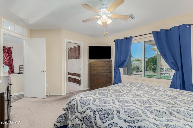 bedroom with ceiling fan, light colored carpet, and ensuite bathroom