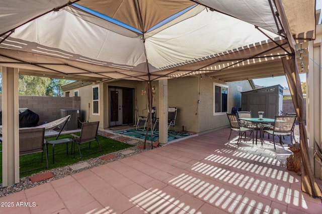 view of patio with cooling unit, area for grilling, and a storage shed