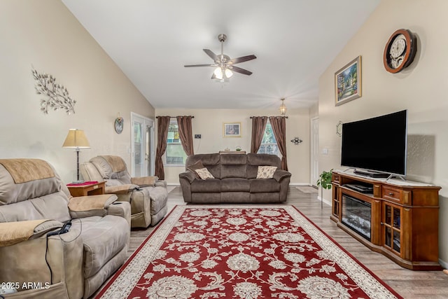 living room with ceiling fan, light hardwood / wood-style flooring, and vaulted ceiling