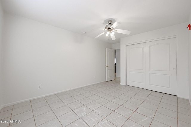 unfurnished bedroom with ceiling fan, light tile patterned flooring, and a closet