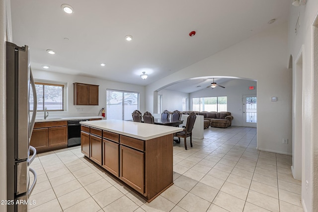 kitchen with ceiling fan, vaulted ceiling, dishwasher, a center island, and stainless steel refrigerator