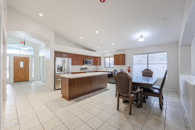 kitchen with a kitchen island, stainless steel appliances, sink, vaulted ceiling, and light tile patterned floors