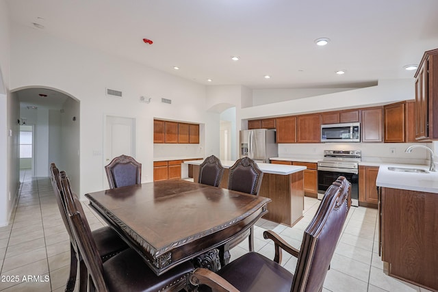 dining space featuring high vaulted ceiling, light tile patterned floors, and sink