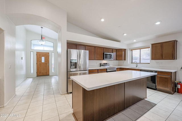 kitchen with pendant lighting, a kitchen island, sink, stainless steel appliances, and light tile patterned floors