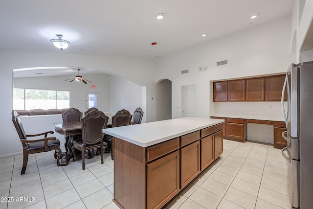 kitchen with ceiling fan, light tile patterned floors, stainless steel fridge, and a center island