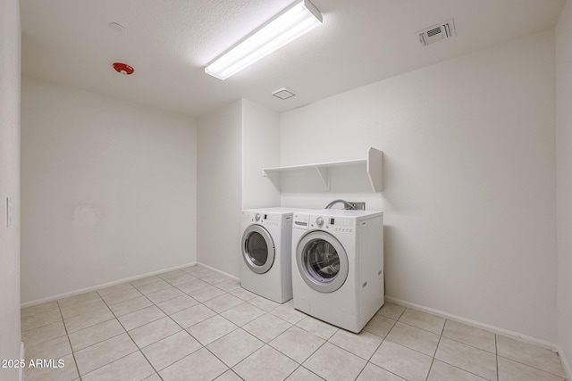 clothes washing area with a textured ceiling, light tile patterned floors, and independent washer and dryer