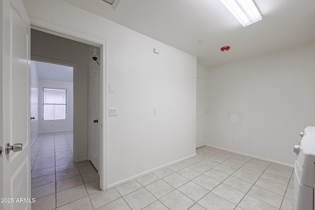 spare room featuring light tile patterned floors, washer and dryer, and a textured ceiling