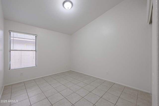 tiled spare room featuring vaulted ceiling