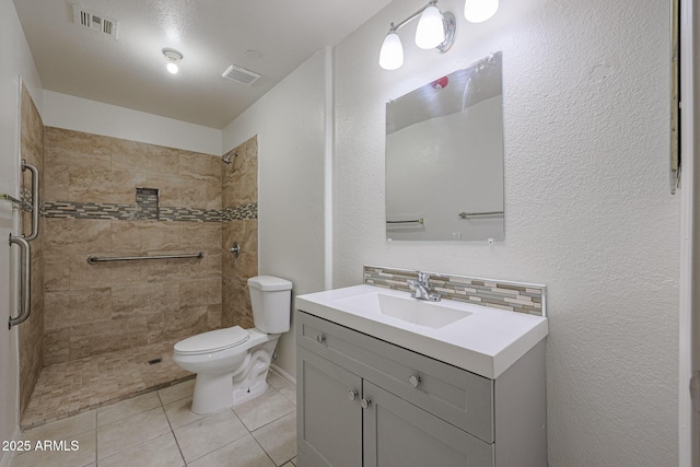 bathroom with tasteful backsplash, vanity, tile patterned flooring, toilet, and tiled shower