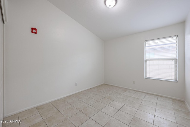 empty room featuring light tile patterned floors and vaulted ceiling