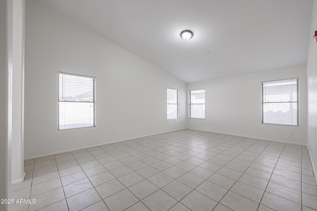 tiled empty room featuring lofted ceiling