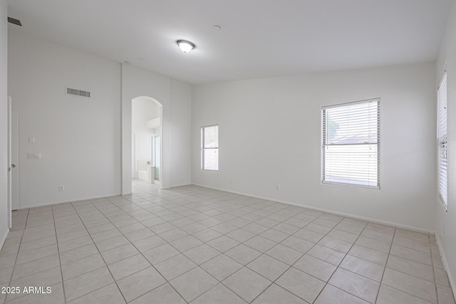 spare room featuring vaulted ceiling and light tile patterned flooring