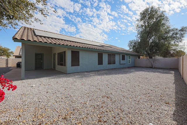 back of house featuring central AC unit, a patio area, and solar panels