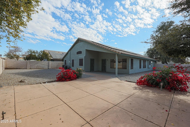 rear view of house with central AC unit and a patio