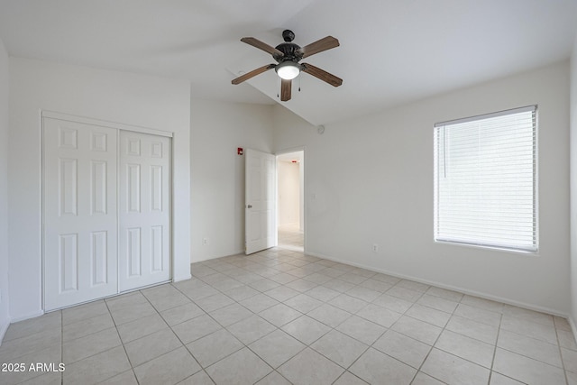 unfurnished bedroom with lofted ceiling, ceiling fan, light tile patterned flooring, and a closet