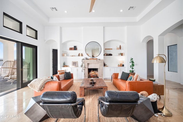 living room with built in shelves, a tray ceiling, and a towering ceiling