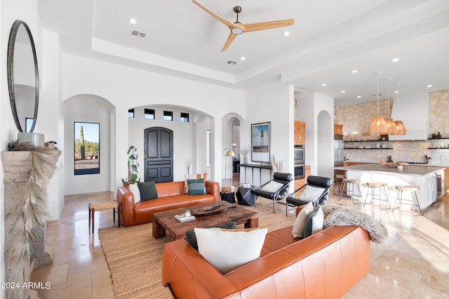 living room with ceiling fan and a raised ceiling