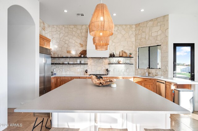 kitchen featuring sink, a breakfast bar, backsplash, appliances with stainless steel finishes, and a center island