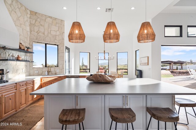 kitchen with decorative backsplash, a kitchen bar, black gas cooktop, sink, and a spacious island