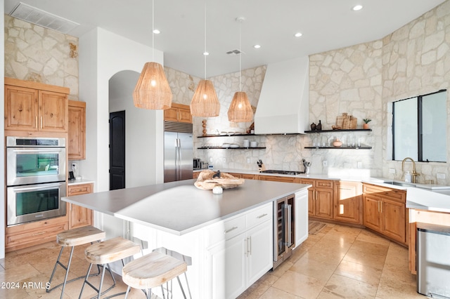 kitchen with appliances with stainless steel finishes, a breakfast bar, a kitchen island, pendant lighting, and custom exhaust hood