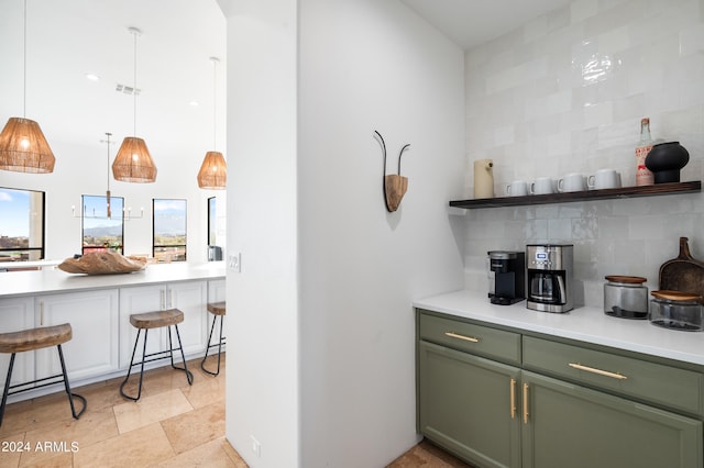 bar featuring green cabinetry, hanging light fixtures, and decorative backsplash