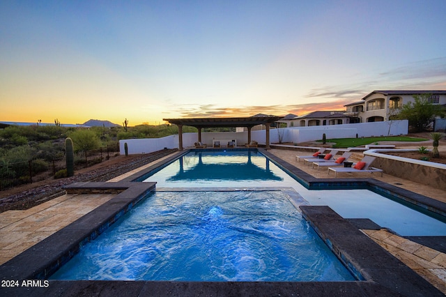 pool at dusk with a patio, a pergola, and an in ground hot tub