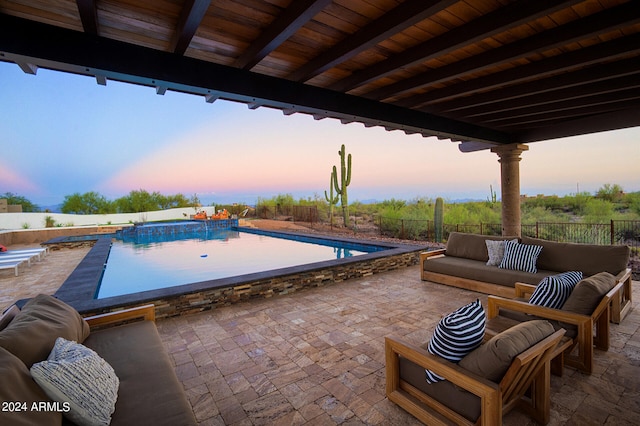 patio terrace at dusk with a fenced in pool and an outdoor living space