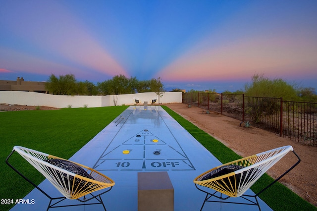 pool at dusk featuring a lawn